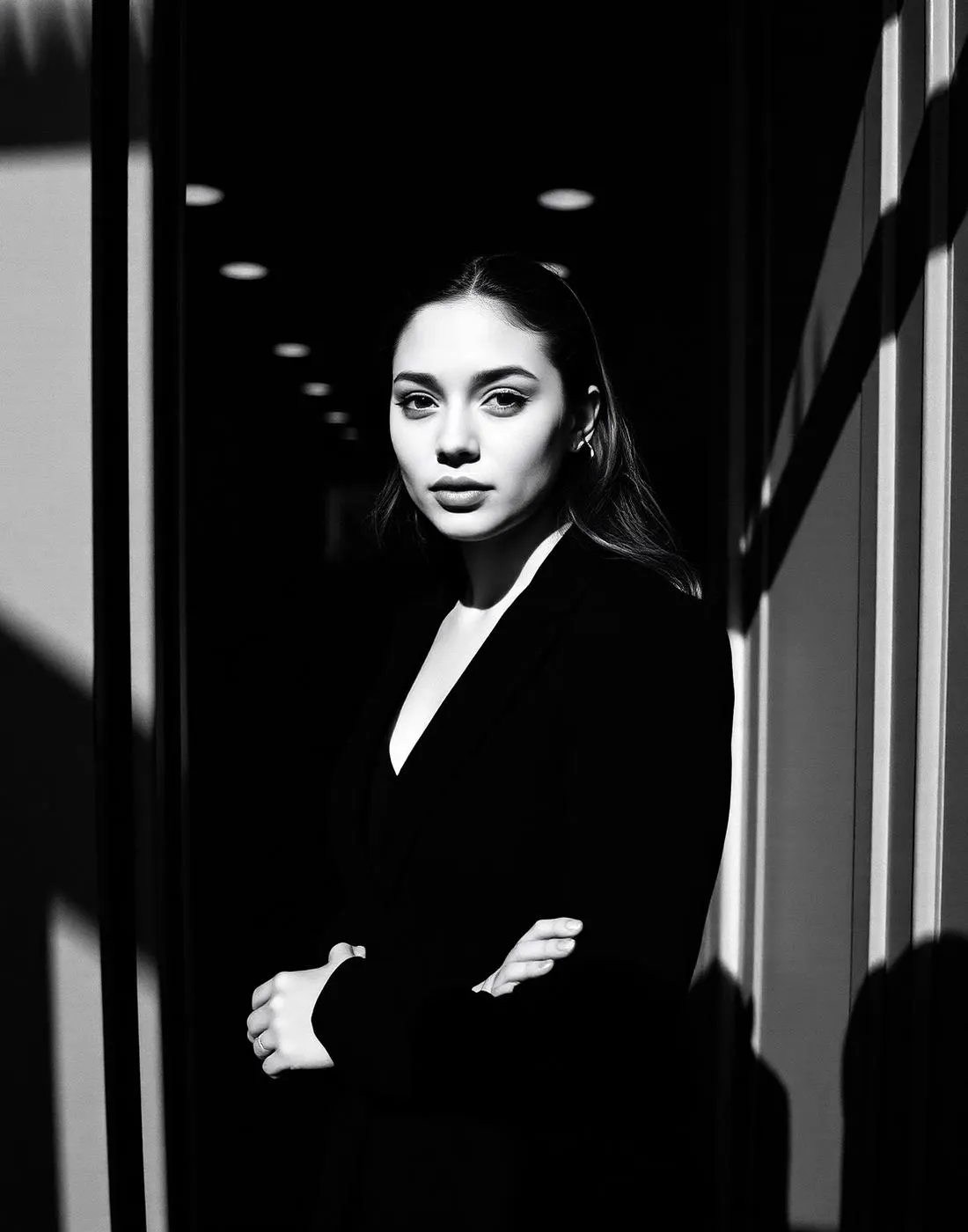 A young professional standing in a storefront doorway in strong contrast light